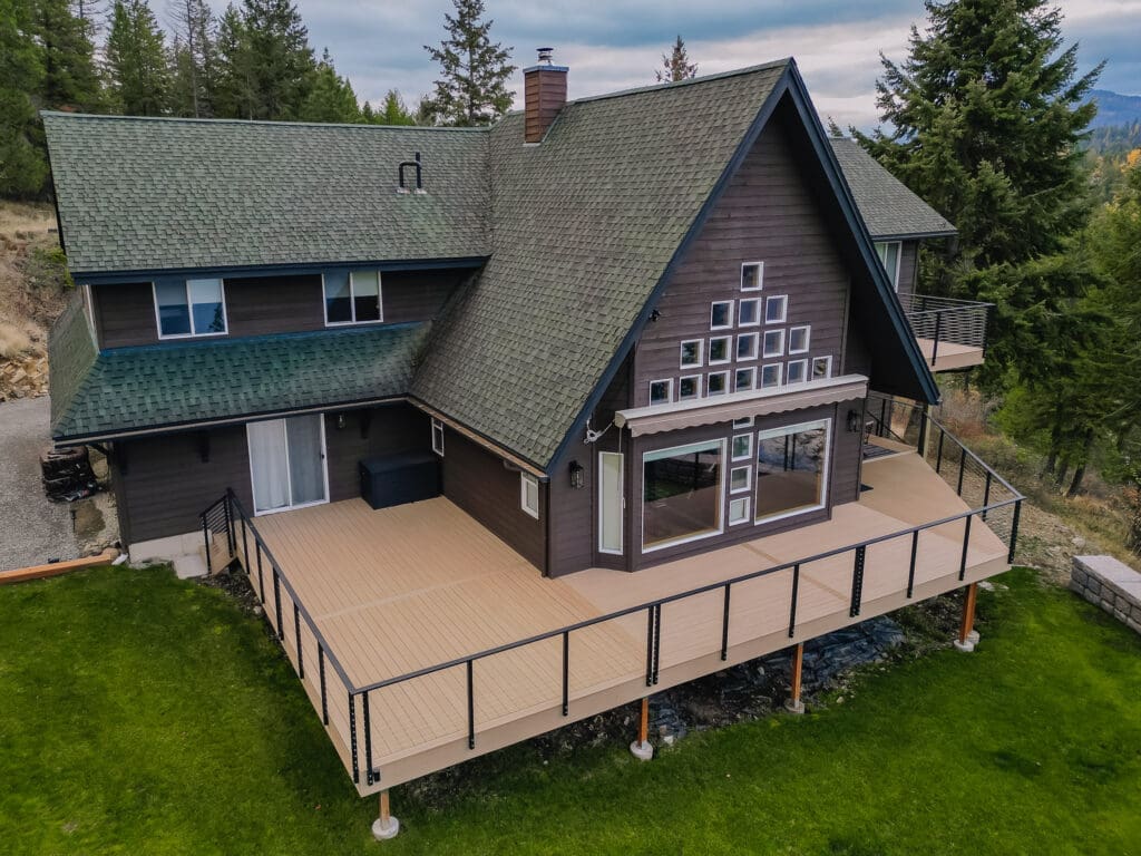 A-frame house with large deck and green roof.