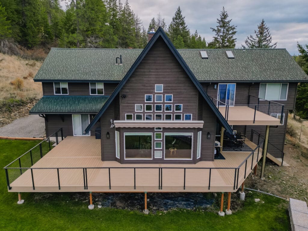 Modern house with large composite deck in mountain setting.