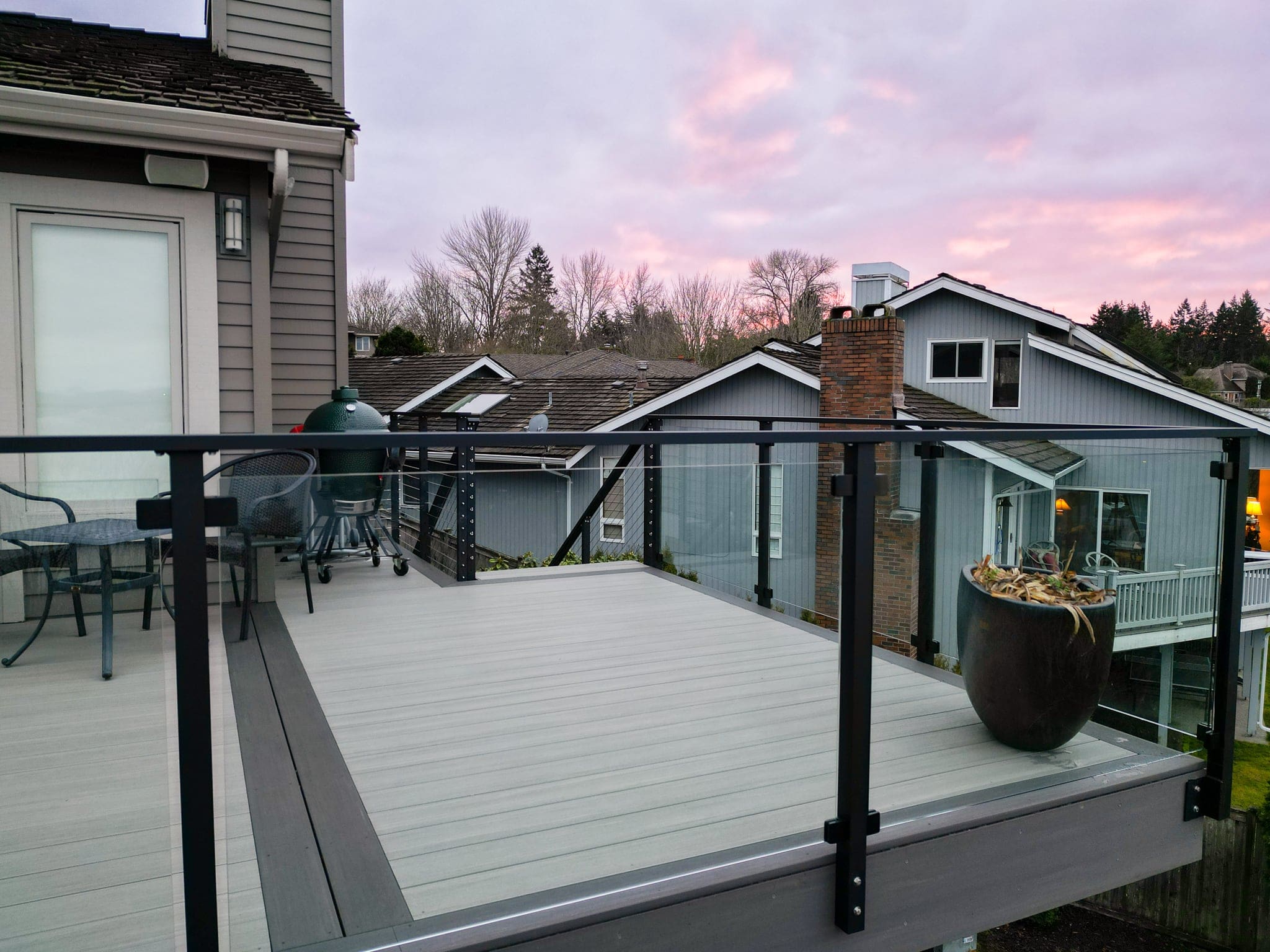Modern deck with framed glass railing at sunset.
