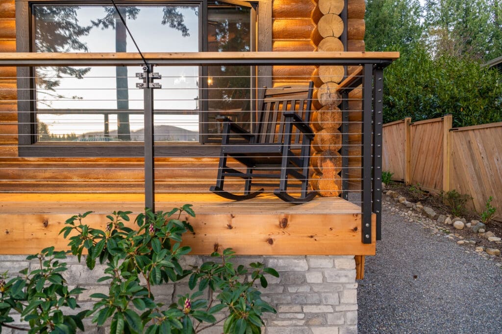 Black rocking chair on wooden porch with cable railing.