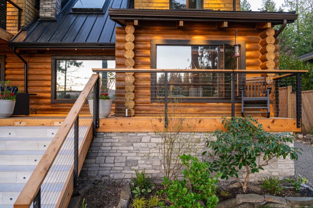 Rustic log cabin exterior with modern deck and railing.
