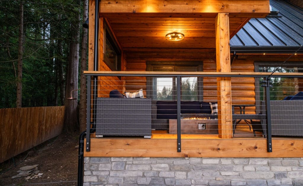 Cozy wooden porch with cushions and fire pit.