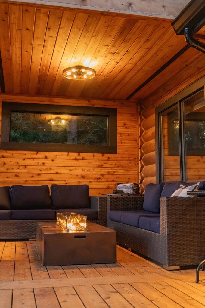 Cozy wooden patio with modern furniture and fireplace.