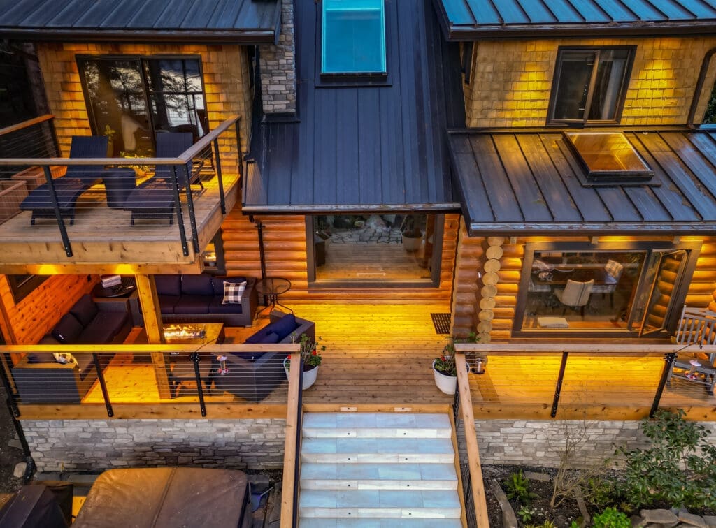 Warm-lit modern cabin exterior with outdoor seating area.