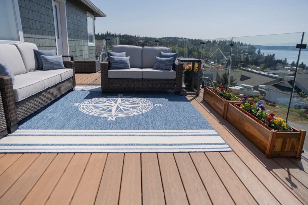 Outdoor deck with blue rug and seating area.