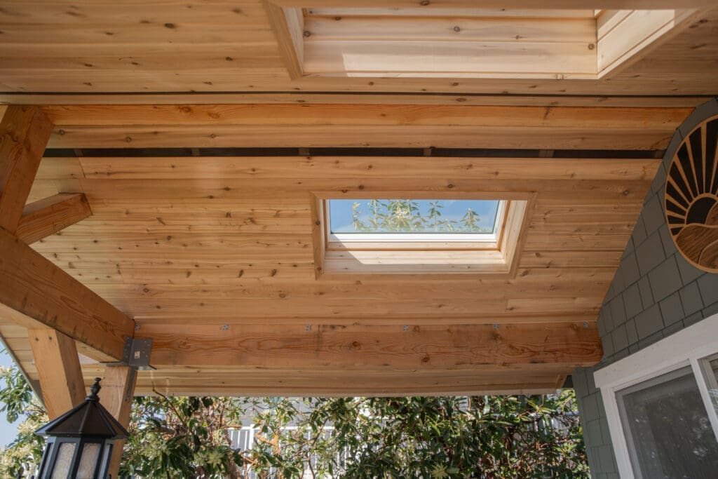 Wooden ceiling with skylight and outdoor greenery view.