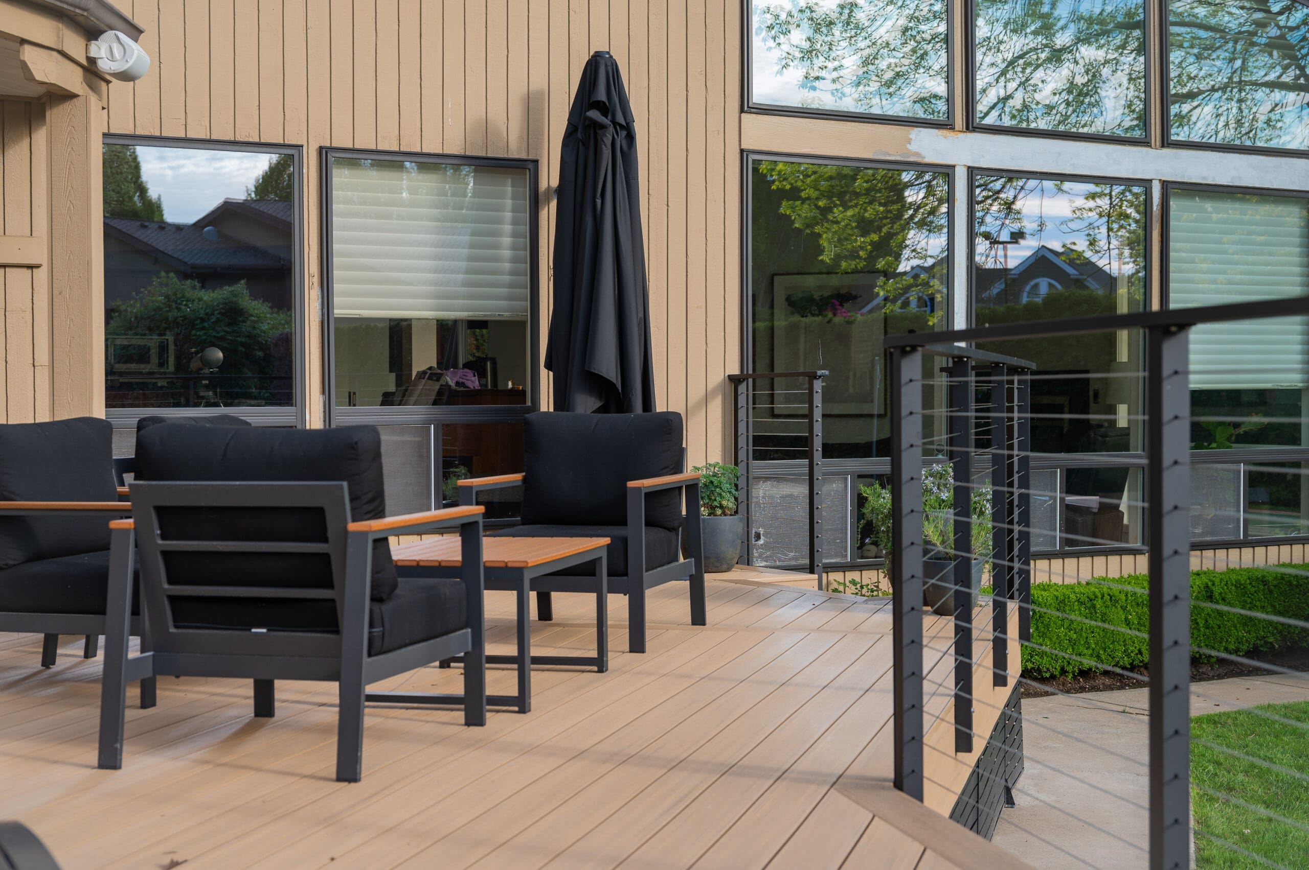 Modern deck with patio furniture and large windows.