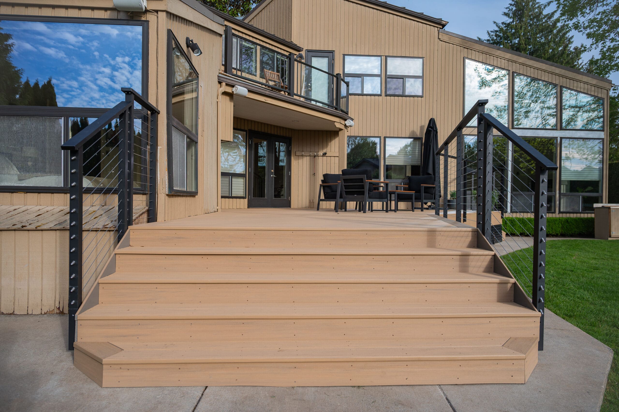 Modern wooden deck with black rails and patio furniture.