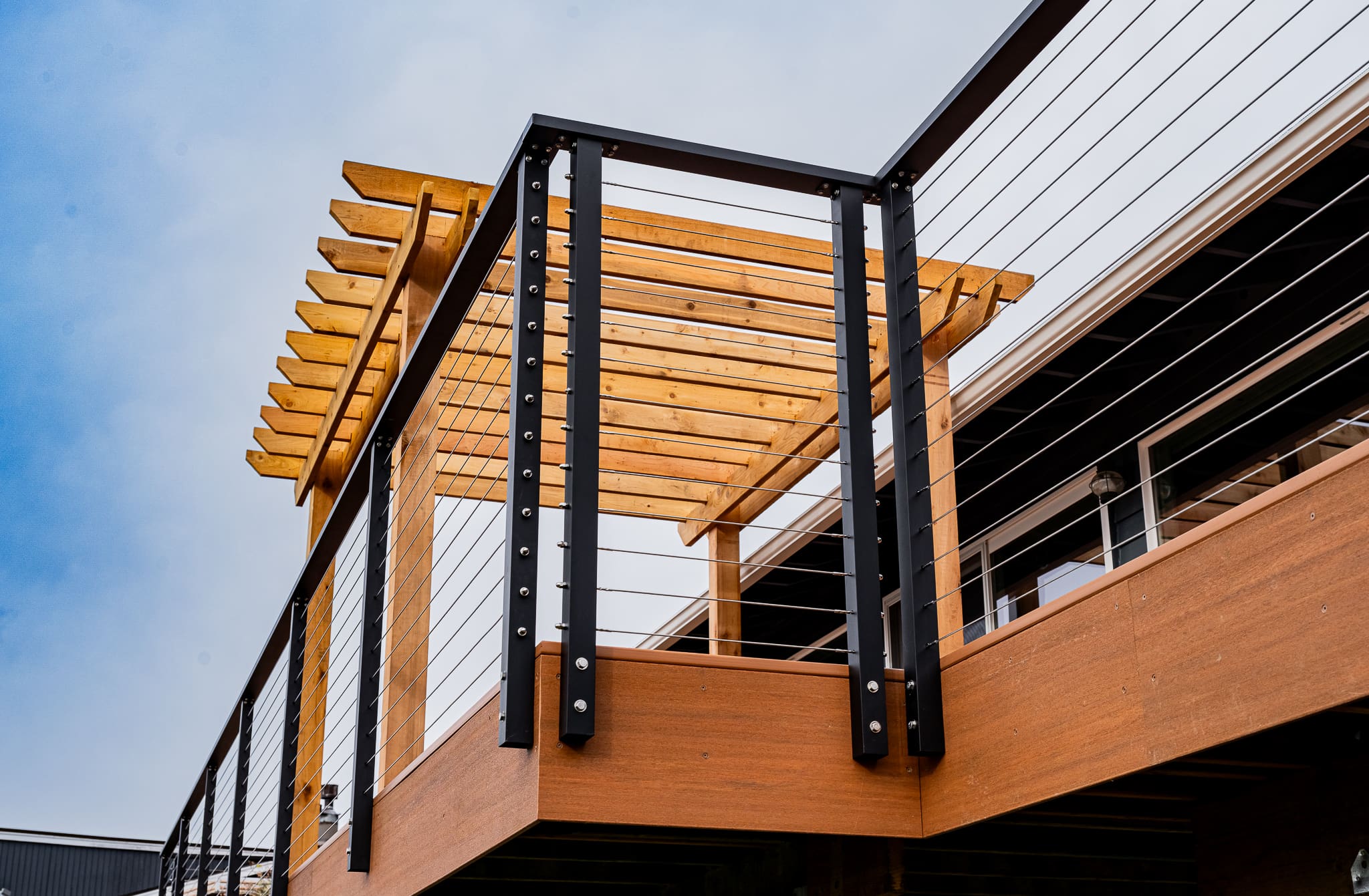 Wooden deck with metal railing and pergola.