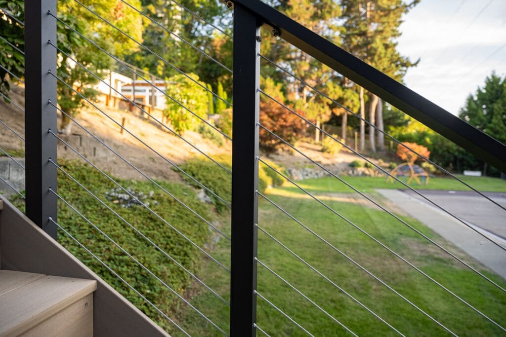 Backyard with cable railing and green landscape view.