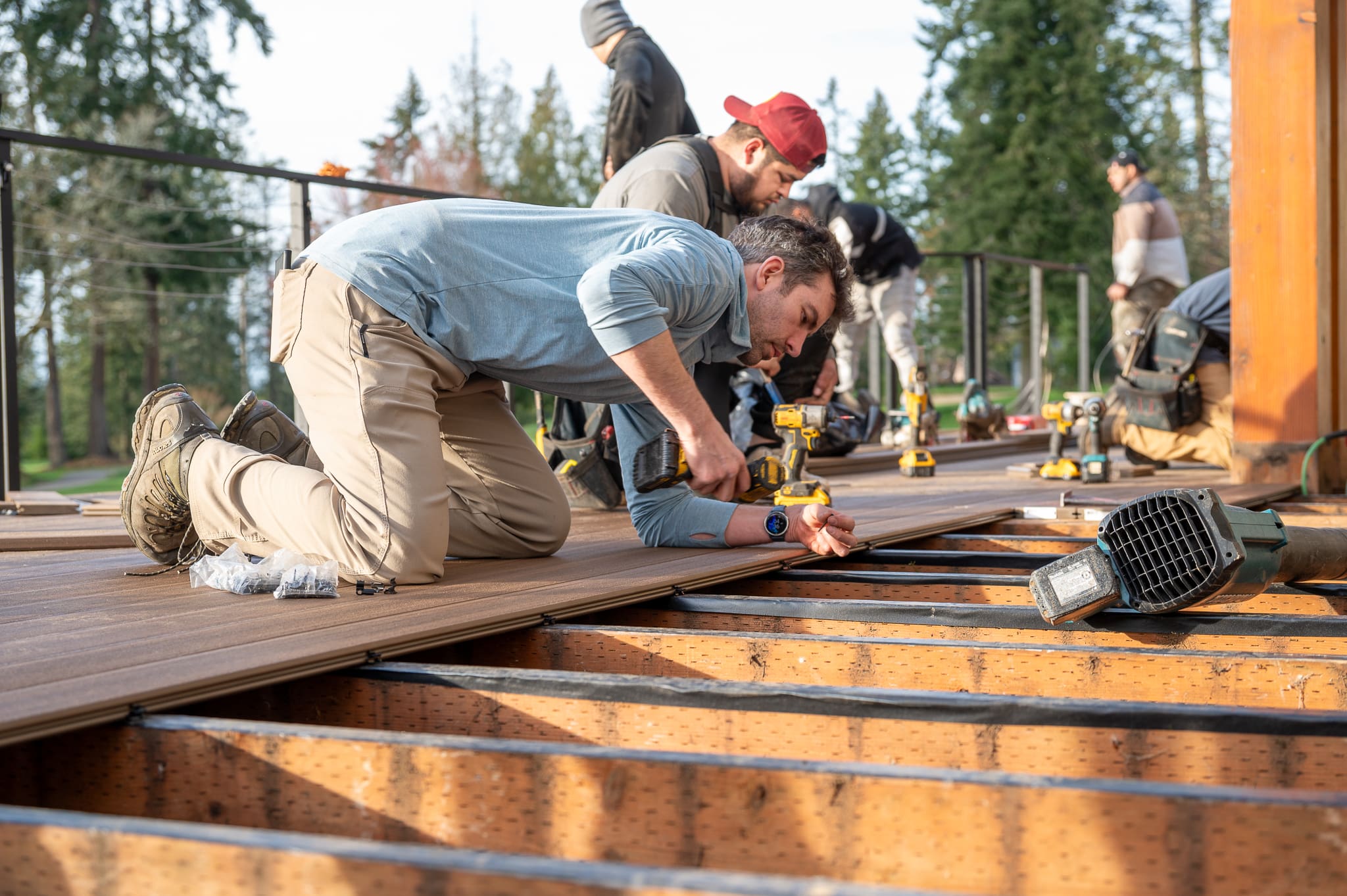 Workers building a wooden deck outside.