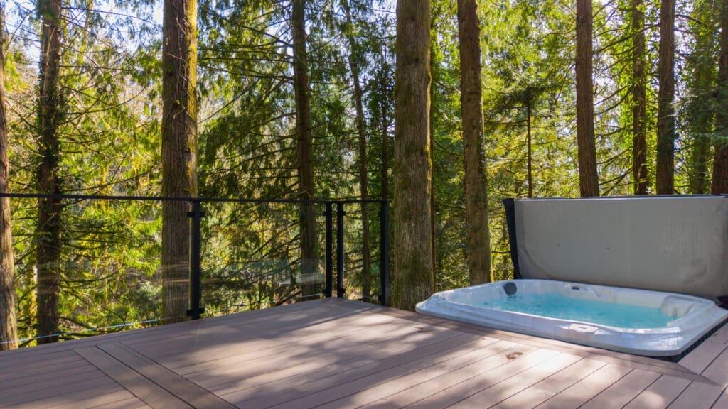 Hot tub on forest deck surrounded by tall trees
