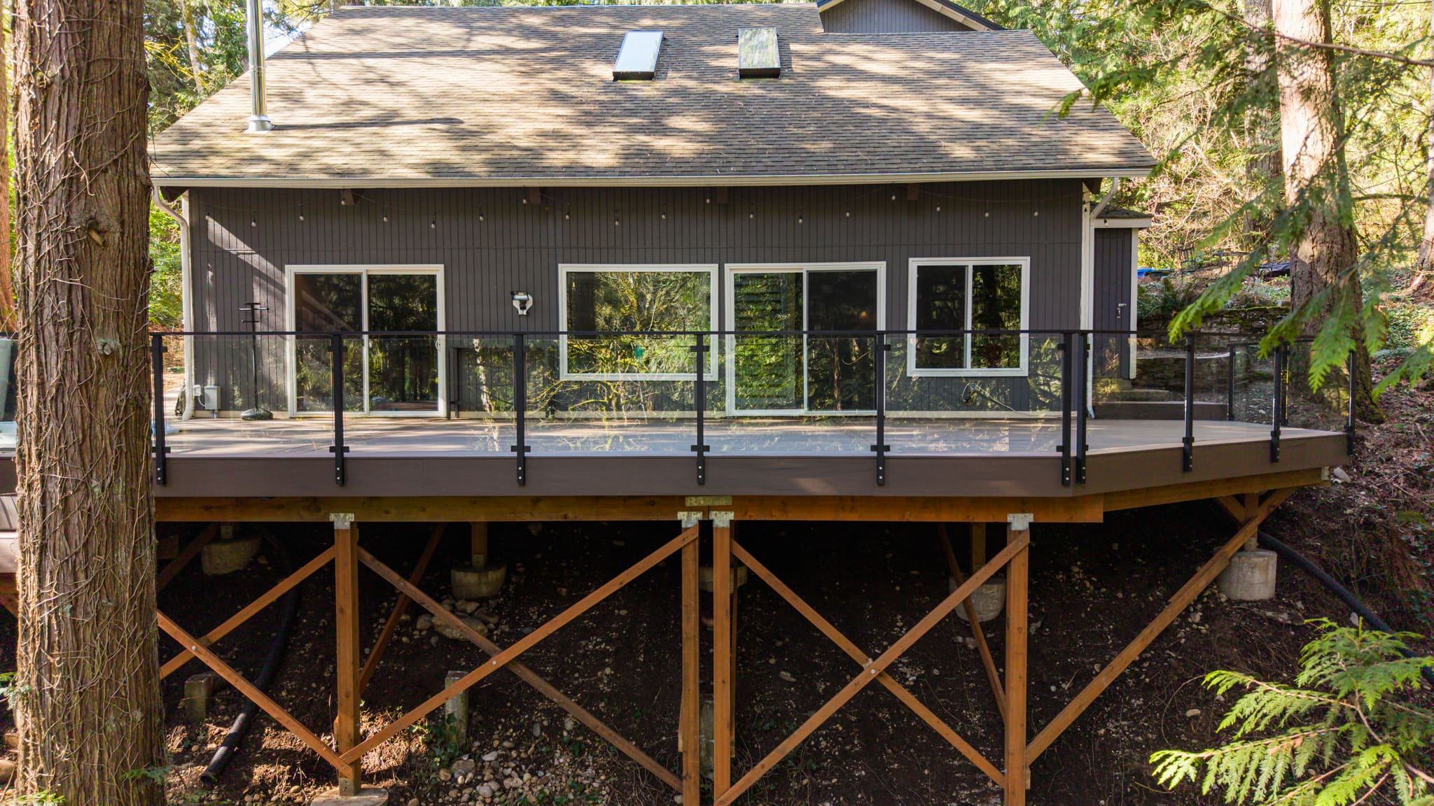 Modern forest home with elevated composite deck on a hillside
