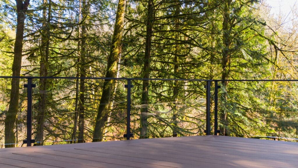 composite deck with framed glass railing overlooking forest