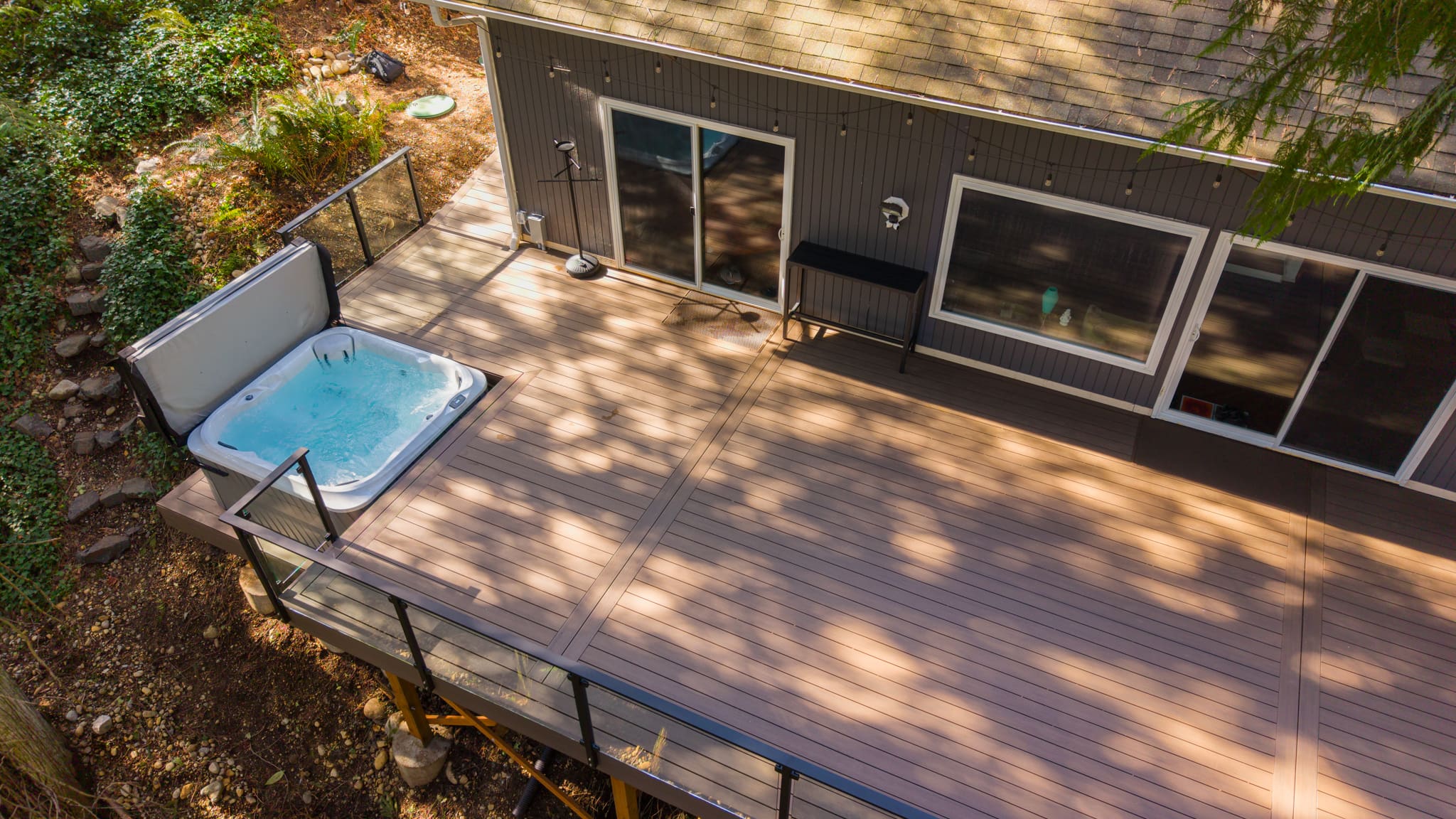 Modern backyard deck with hot tub and glass railing