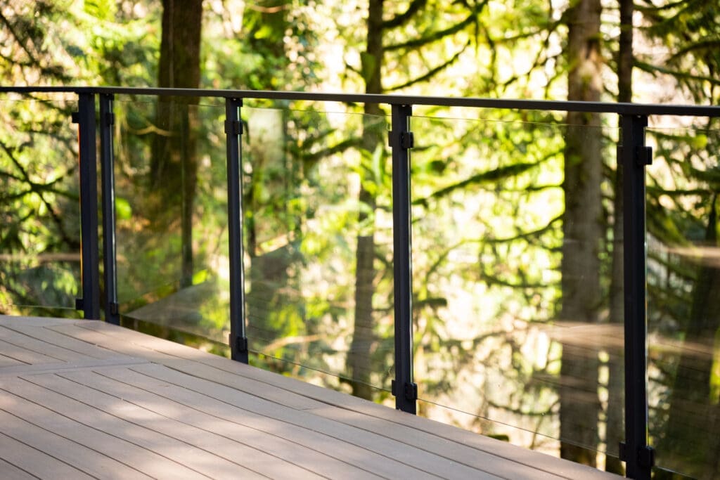 Modern glass deck railing overlooking lush forest