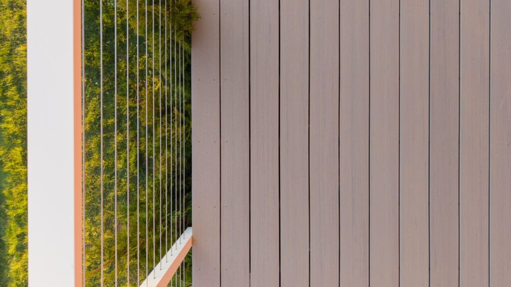 Modern wooden balcony with glass railing and greenery