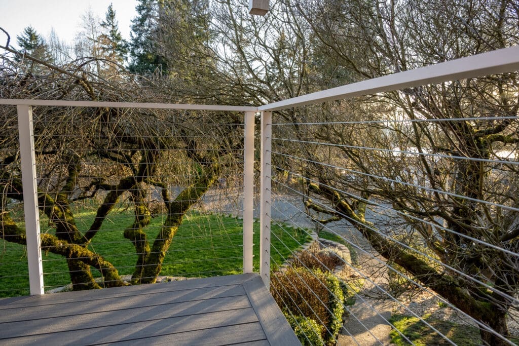 Deck with cable railing overlooking mossy trees and river