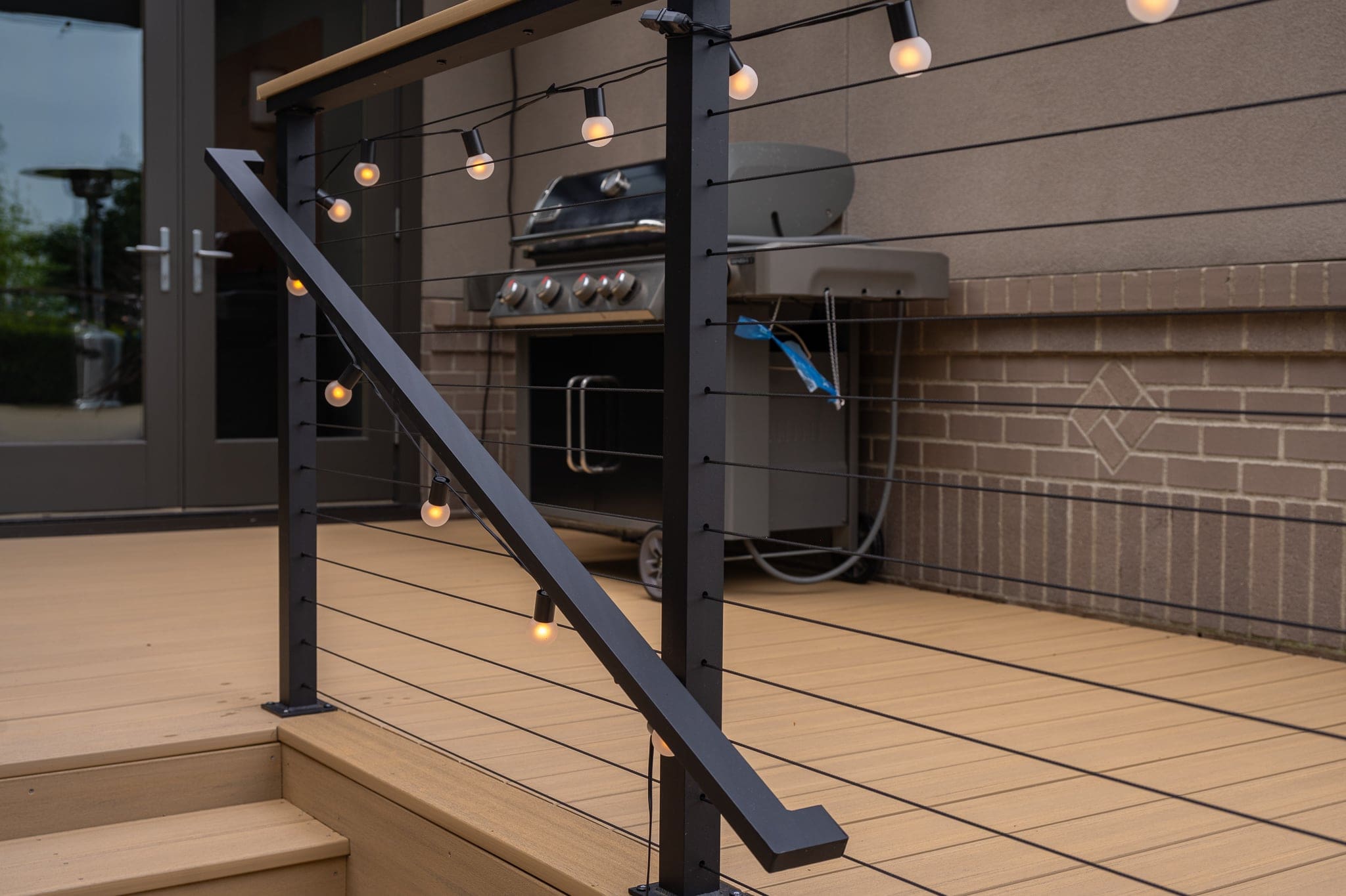 Modern deck railing with string lights and grill